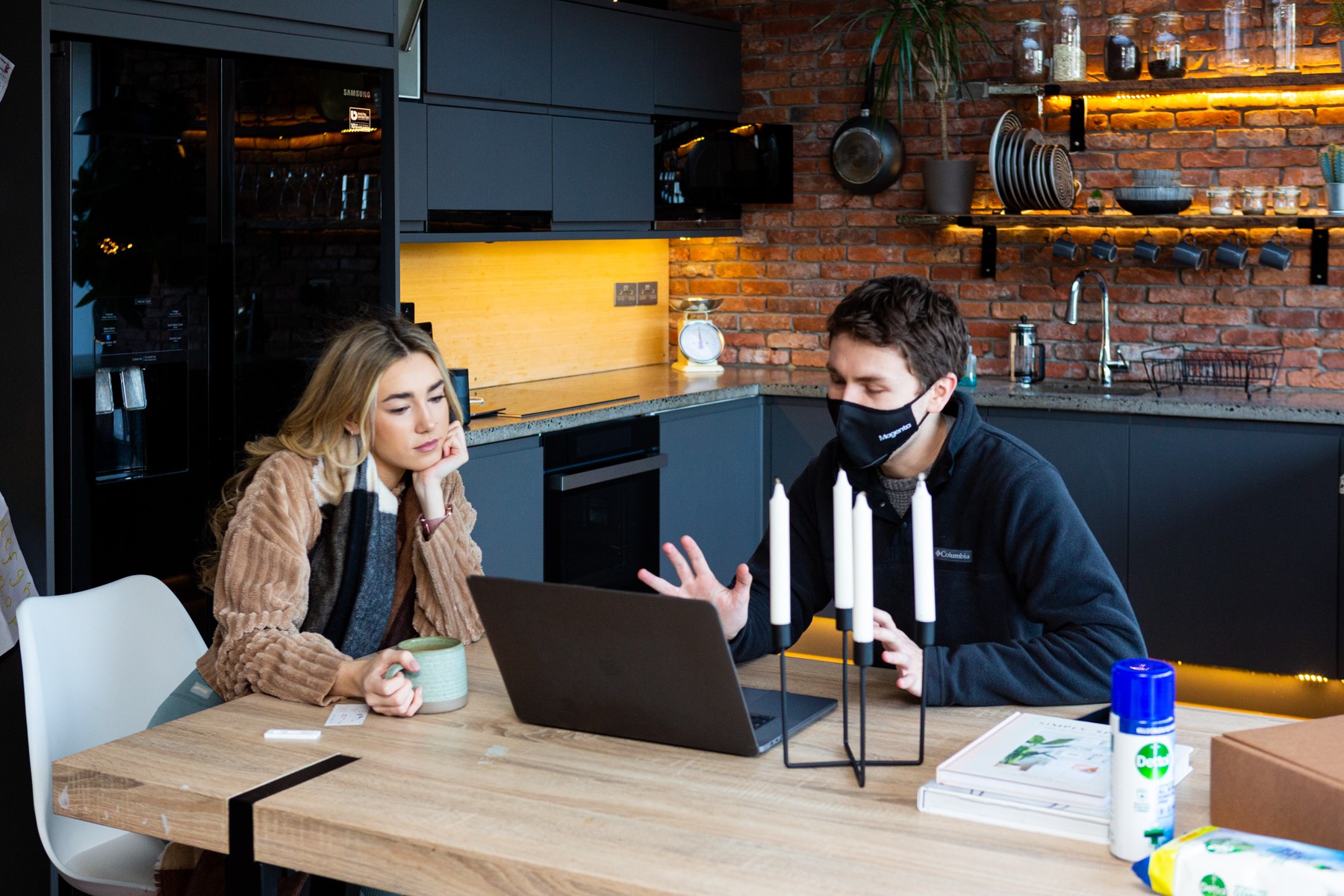A member of our team wearing a face mask while talking to a client about what's on the computer screen